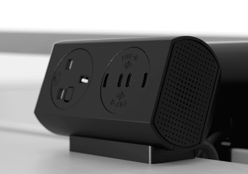 Close-up of a black multi-outlet power dock with two USB ports and three slots on a desk.