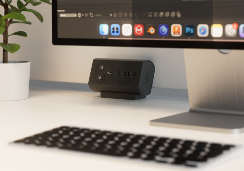 Compact black power hub with two outlets and USB ports on a white desk beneath a monitor.